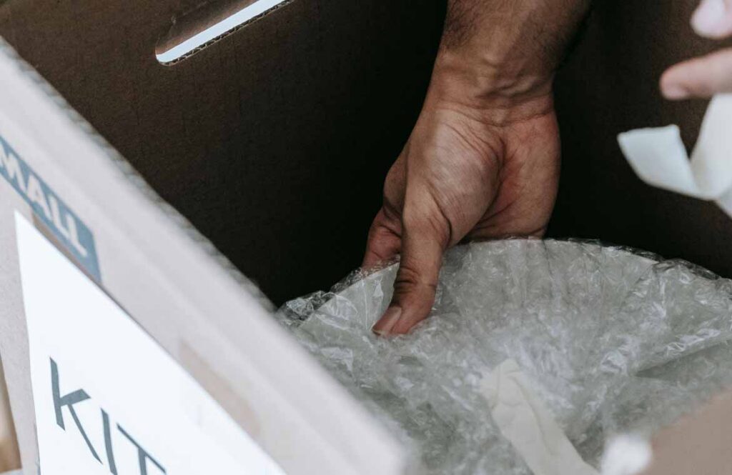 Kitchen items wrapped and packed upright into a small labelled cardboard moving carton