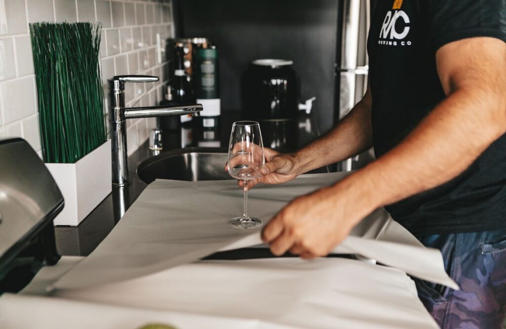 Wine glasses wrapped in packing paper and standing upright in a divided moving box
