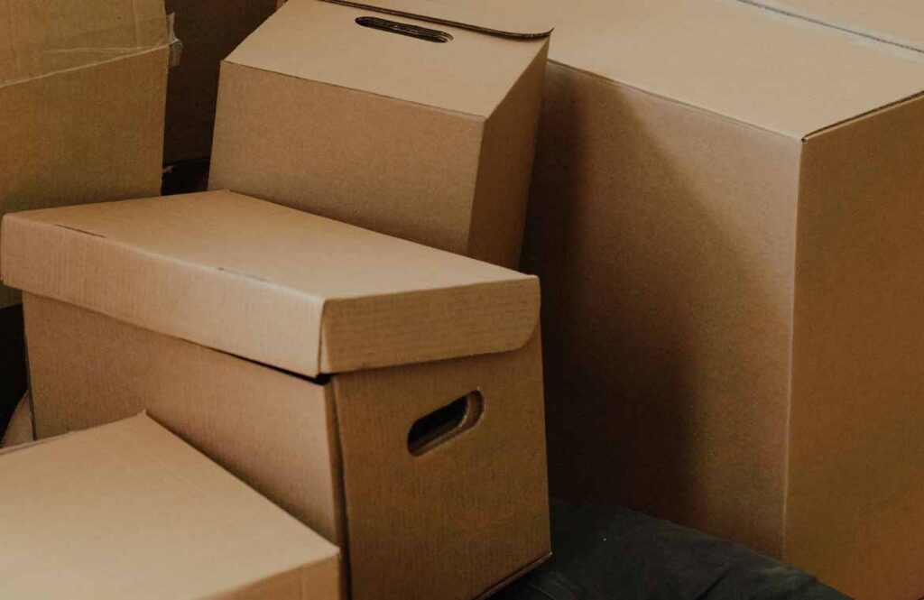 Labelled cardboard moving boxes stacked by room in a hallway during a house move Labelled cardboard moving boxes stacked by room in a hallway during a house move
