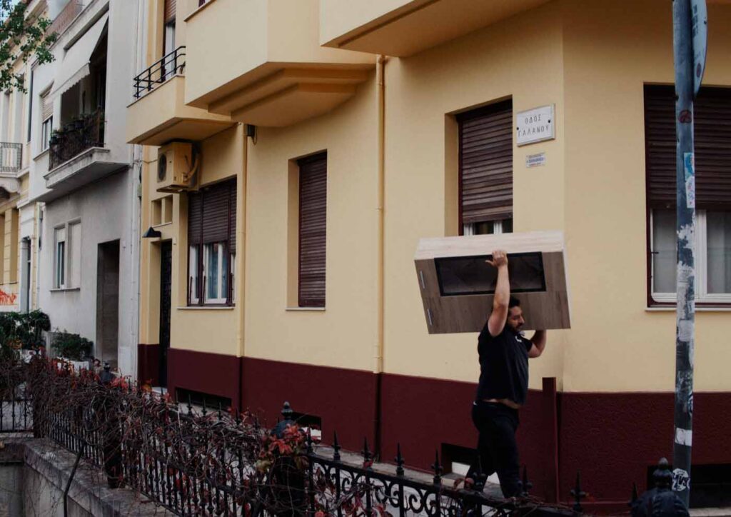 A mover carrying a box along an inner-city street during a Central Auckland house move