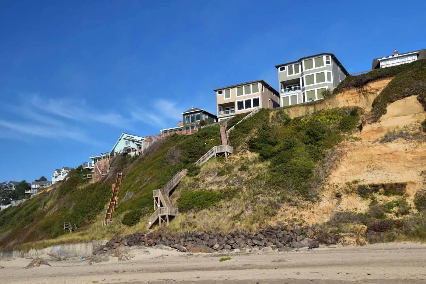 Coastal homes on a steep slope above the water, typical Eastern Bays access with steps down from the road